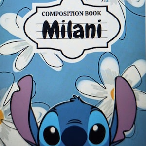 May include: A composition book with a light blue background featuring white daisy flowers. A central white label contains the text COMPOSITION BOOK and the name Milani in black. Below the label is a blue character with large ears and eyes.