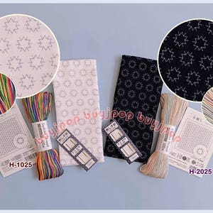 May include: An assortment of embroidery supplies, including spools of colorful thread, fabric samples with star patterns, and instruction cards. The color palette includes white, black, and various shades of rainbow colors. The instruction cards have the text "H-1025" and "H-2025".