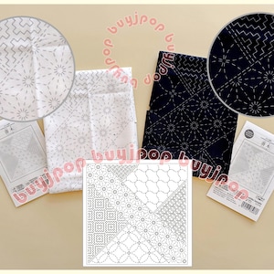 Pode incluir: Uma variedade de tecidos e padrões sashiko japoneses. A imagem mostra tecido branco e azul marinho com designs intrincados costurados, juntamente com guias de padrões. Os designs incluem formas geométricas e padrões de estrelas.