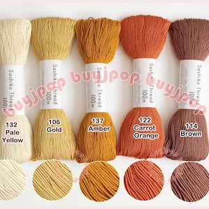 May include: Five spools of Sashiko Thread in various colors: Pale Yellow, Gold, Amber, Carrot Orange, and Brown. Each spool is labeled with its color and the text "Sashiko Thread 100m".