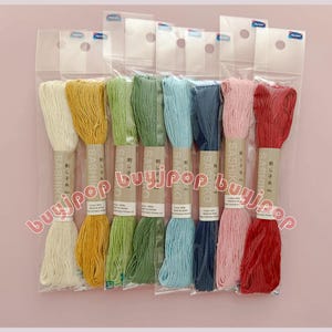 May include: A collection of embroidery floss in various colors, including white, yellow, green, blue, pink, and red. Each skein is wrapped with a paper label. The floss is packaged in a clear plastic bag.