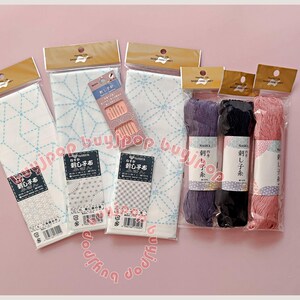 Kit de iniciación Sashiko F - Japón Naska. Tres patrones de muestrario Sashiko preimpresos. Tela blanca, 3 madejas de hilo de 80 m (marrón, rojo y violeta), 6 agujas.