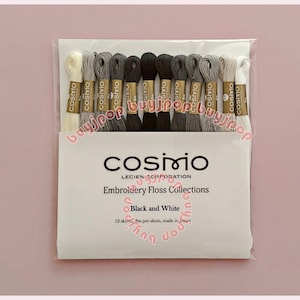 May include: A set of 12 Cosmo embroidery floss skeins in a gradient of black, white, and grey shades. The packaging is labelled Cosmo Lecien Corporation Embroidery Floss Collections Black and White, noting 12 skeins, 8m per skein, made in Japan.