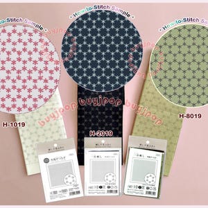 Puede incluir: Tres kits de bordado en tela etiquetados H-1019, H-2019 y H-8019. Cada kit incluye una tela doblada con un patrón repetitivo similar a un copo de nieve en rosa, azul oscuro o verde, y un paquete de plástico transparente con instrucciones y diseño.