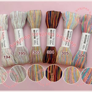 May include: Six skeins of Sashiko Thread in various colors, each labeled with a number and "100m". The colors include cream, light brown, yellow, orange, red, blue, and green. The thread is wrapped around a white label.