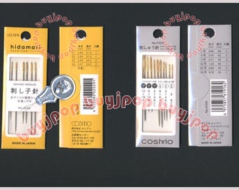 Puede incluir: Cuatro paquetes de agujas de coser, cada uno con una marca y un tamaño diferentes. Los paquetes son amarillos, blancos y plateados. Las agujas están dispuestas en filas y todas son del mismo tamaño. Los paquetes están etiquetados con el nombre de la marca, el tamaño y el país de origen. El texto en los paquetes está en japonés.