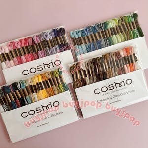 May include: Four Cosmo embroidery floss collections in various color palettes. Each collection includes multiple skeins of thread in shades of pink, blue, green, yellow, and brown. The packaging features the Cosmo logo and text.