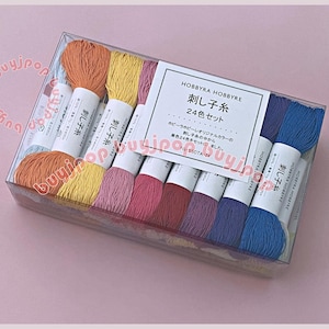 May include: A clear rectangular plastic box containing 24 skeins of embroidery thread in various colors including orange, yellow, pink, red, purple, and blue. Each skein has a white paper label with Japanese text reading HOBBYRA HOBBYRE.