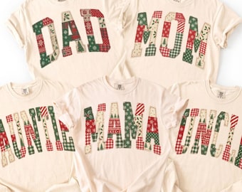 May include: Five off-white short-sleeve t-shirts featuring large block letters with a red, green, and white holiday-themed patchwork pattern. The shirts display the words DAD, MOM, AUNTIE, MAMA, and UNCLE in a collegiate-style font across the chest.