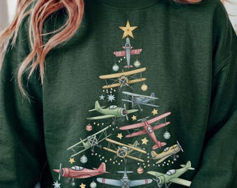 Op de afbeelding: Een donkergroen sweatshirt met lange mouwen voorzien van een grafische print van diverse vintage vliegtuigen gerangschikt in de vorm van een kerstboom, geaccentueerd met kleine gele sterren en ronde ornamenten.