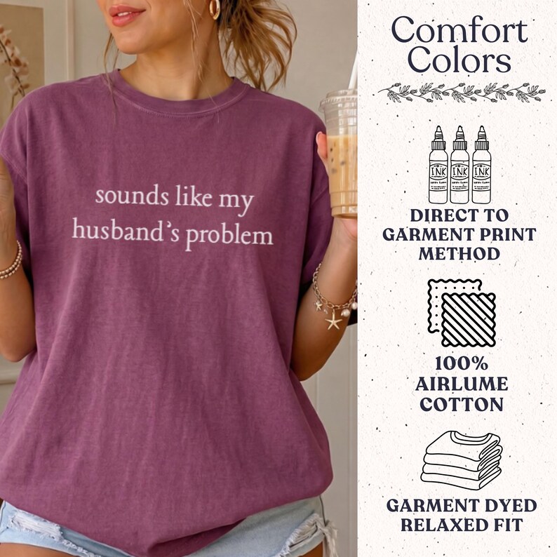 May include: A plum-colored short-sleeve t-shirt with the white text "sounds like my husband's problem" printed on the front. The side panel displays Comfort Colors branding, direct to garment print method, 100% airlume cotton, and relaxed fit.