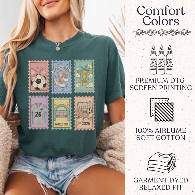 May include: Dark teal t-shirt featuring six postage stamp designs with soccer-themed graphics. The stamps include a soccer ball, shoes, a trophy, a jersey with the number 26, a soccer goal, and the text "World Cup 2026". The shirt also has the text "Comfort Colors".