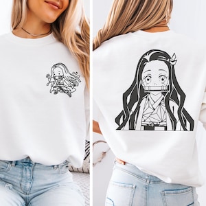 May include: A white crewneck sweatshirt featuring a small black graphic of a long-haired anime character on the front left chest and a large black graphic of the same character on the back, both depicting a figure with a bamboo muzzle.