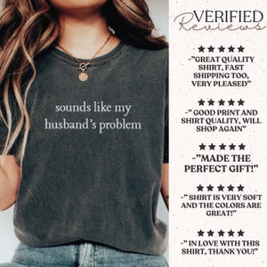 May include: A charcoal gray short-sleeve t-shirt with the white text "sounds like my husband's problem" printed on the chest. To the right, a list of five-star verified reviews is displayed, featuring customer feedback about the shirt quality.