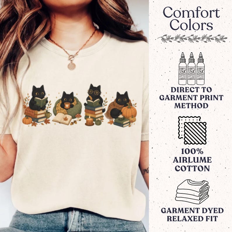 May include: A cream-colored t-shirt featuring a graphic of four black cats with books, pumpkins, and autumn leaves. The text on the right side reads Comfort Colors, Direct to Garment Print Method, 100% Airlume Cotton, and Garment Dyed Relaxed Fit.