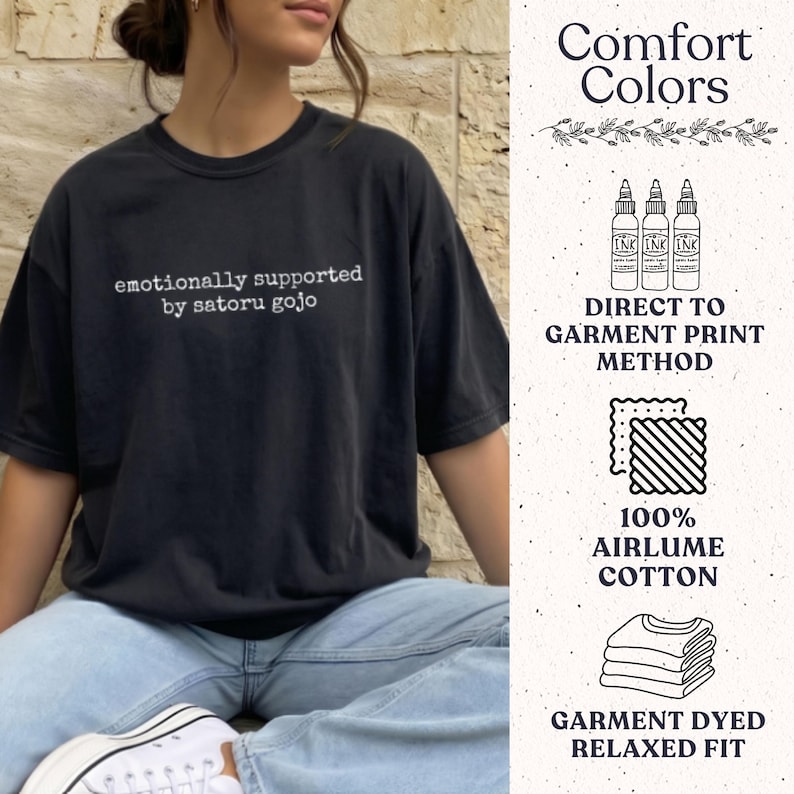 May include: A black short-sleeve t-shirt with the white text "emotionally supported by satoru gojo" printed on the chest. The shirt features a relaxed fit and is made of 100% airlume cotton, utilising a direct to garment print method.