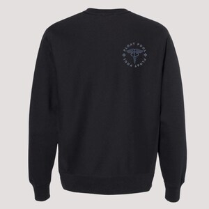 May include: A black long-sleeve crewneck sweatshirt featuring a circular graphic on the upper right chest. The design includes a caduceus symbol in the center surrounded by the text FLOAT POOL and small cross icons in a dark gray color.
