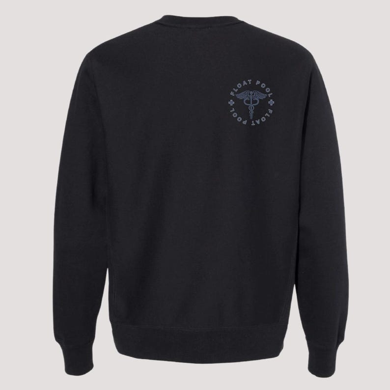 May include: A black long-sleeve crewneck sweatshirt featuring a circular graphic on the upper right chest. The design includes a caduceus symbol in the center surrounded by the text FLOAT POOL and small cross icons in a dark gray color.