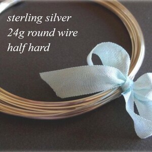 May include: A bundle of sterling silver 24g round wire, half hard, tied with a light blue ribbon. The wire is coiled and appears shiny. Text on the image reads "sterling silver 24g round wire half hard."