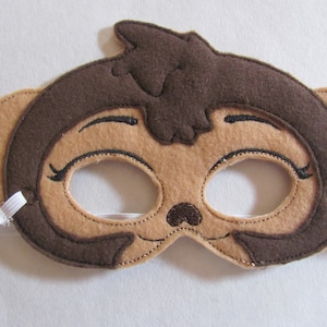 May include: A brown felt monkey mask with white elastic straps. The mask has embroidered eyes, a nose, and a mouth.