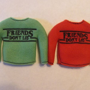 May include: Two long-sleeved shirts with the text "Friends Don't Lie" in black lettering on a green and red shirt.