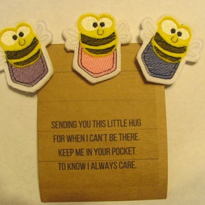 May include: Three embroidered bee pocket hug patches with a message on a brown card that reads: "Sending you this little hug for when I can't be there. Keep me in your pocket to know I always care."