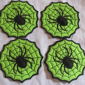 May include: Four green and black fabric coasters with a spider web and spider design.