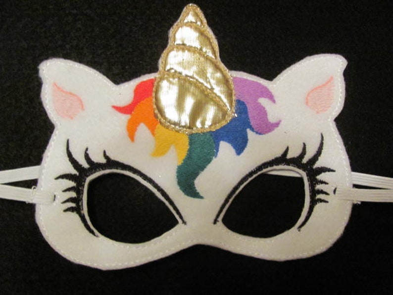 May include: White felt unicorn mask with a rainbow mane and a gold horn. The mask has black eye holes and elastic straps.