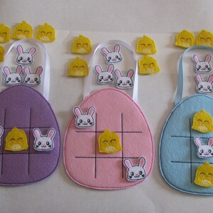 May include: Three felt Easter egg tic-tac-toe games with bunny and chickie pieces. The games are purple, pink, and blue.