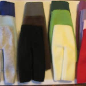 May include: Seven pairs of fleece pants in various colors, including blue, gray, black, brown, green, cream, red, pink, and purple. The pants are all folded in half and arranged in a row.