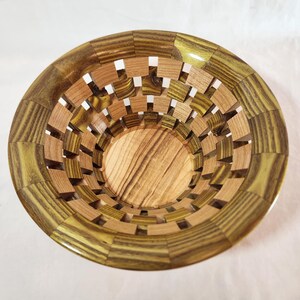 May include: A wooden bowl with a lattice design. The bowl is made of light and dark wood, creating a striped pattern. The bowl is empty.