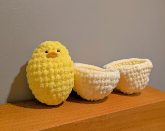 May include: A yellow crocheted chick toy with a beak and eyes, sitting next to two white crocheted egg-shaped bowls.