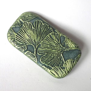 May include: A green and gold rectangular polymer clay pendant with a ginkgo leaf design.