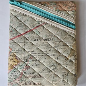 May include: A quilted fabric pouch with a zipper closure. The pouch is decorated with a vintage world map print featuring the Pacific Ocean, the Kuril Islands, and the Japanese islands. The zipper is teal blue.