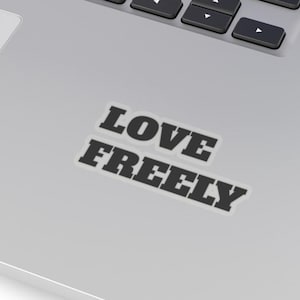 May include: A silver laptop with a black sticker that says "LOVE FREELY" on the top right corner of the laptop.