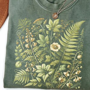 a green t-shirt with a detailed floral and leaf pattern printed on it.