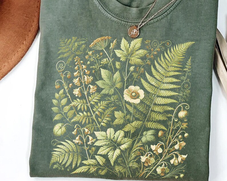 a green t-shirt with a detailed floral and leaf pattern printed on it.