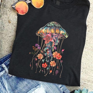 May include: A black t-shirt with a colorful jellyfish graphic. The jellyfish is surrounded by flowers in shades of pink, orange, and yellow. The jellyfish has a bell-shaped body and long, flowing tentacles.