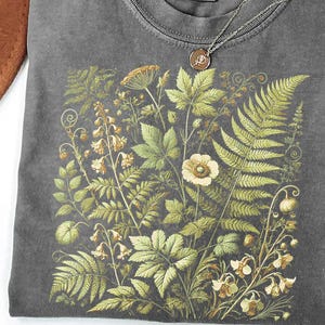 a gray t-shirt with a detailed floral and leaf pattern printed on it.
