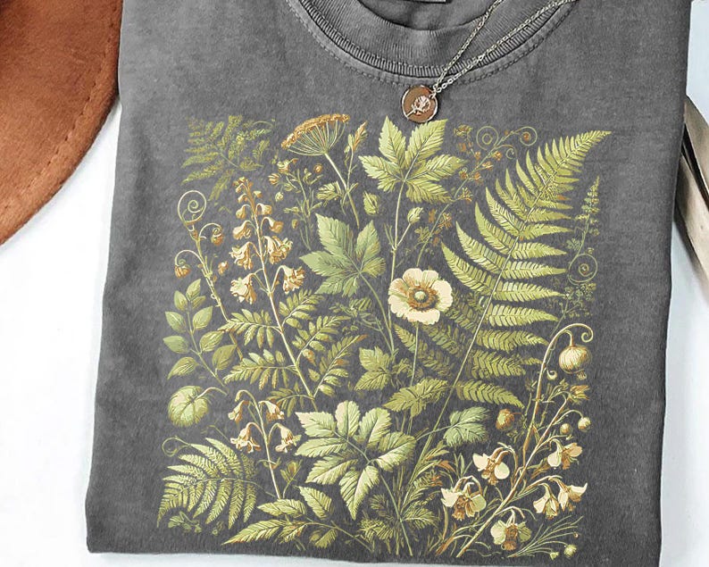 a gray t-shirt with a detailed floral and leaf pattern printed on it.