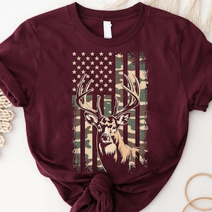A burgundy t-shirt with a graphic design featuring a deer's head and an American flag pattern.
