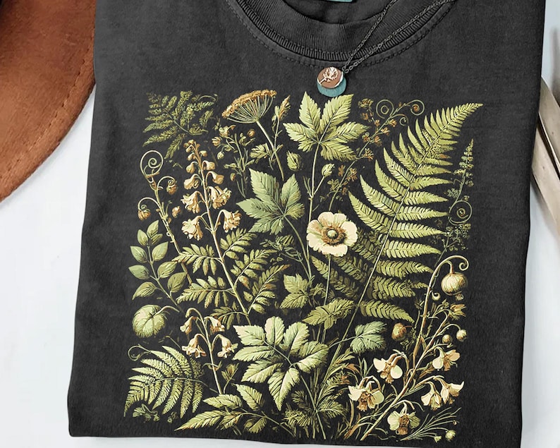 a black t-shirt with a detailed floral and leaf pattern printed on it.