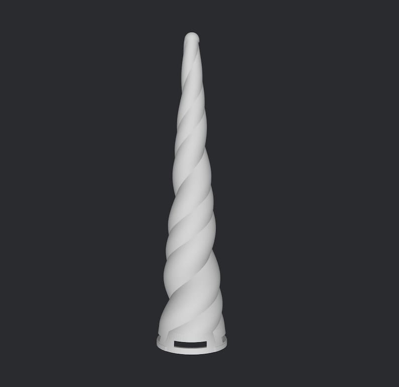 Peut inclure: Une corne de licorne blanche avec un motif en spirale. La corne est de couleur unie et a un aspect lisse et &eacute;pur&eacute;. La base de la corne comporte une petite ouverture rectangulaire. Le fond est gris fonc&eacute;.