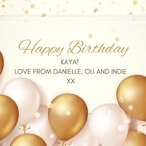 May include: A birthday greeting card with gold and white balloons. The card features the text "Happy Birthday KAYA! LOVE FROM DANIELLE, OLI AND INDIE XX" in elegant gold script against a cream background.