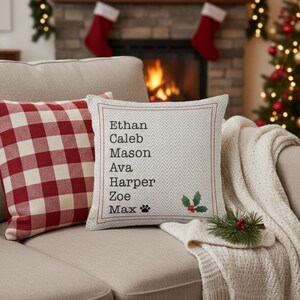 May include: Two decorative throw pillows on a beige sofa. One pillow has a red and white checkered pattern. The other pillow is light gray with a herringbone design and the names Ethan, Caleb, Mason, Ava, Harper, Zoe, and Max.