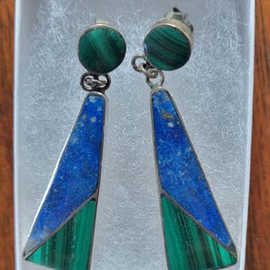 May include: A pair of dangle earrings with a geometric design. The earrings are made of silver and feature blue and green stones.