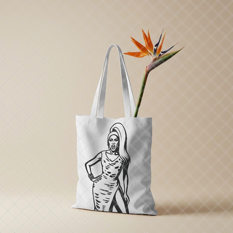May include: A white tote bag featuring a black and white graphic illustration of a person with long hair wearing a sleeveless dress. A single orange and blue bird of paradise flower is placed inside the bag, extending upwards from the opening. This image is part of the RuPaul Drag Race Clipart Bundle, Queen of Drag SVG PNG JPG digital download.
