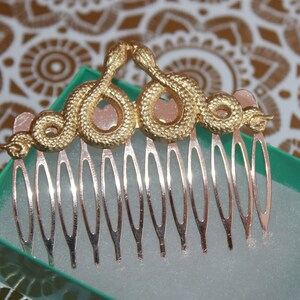 May include: Gold snake hair comb with a silver comb base. The snake is curled into a crown shape.