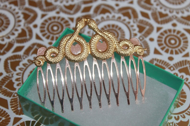 May include: Gold snake hair comb with a silver comb base. The snake is curled into a crown shape.