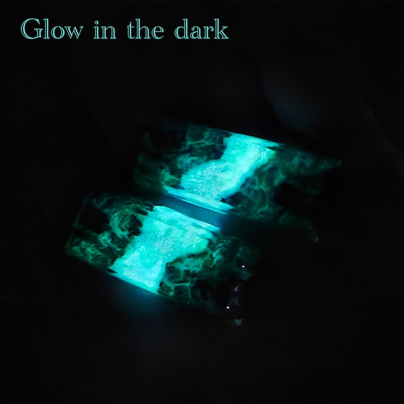 May include: Two pieces of dark green and black resin with a swirling pattern that glows bright blue in the dark. "Glow in the dark" is written in white text at the top of the image.